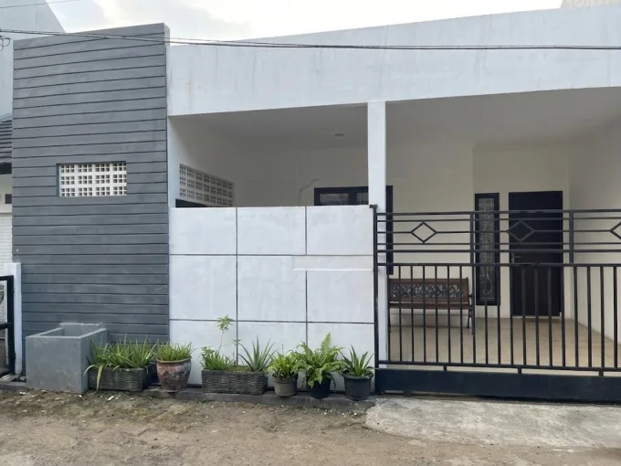 Modern white and gray house facade with a black metal gate and row of potted plants along the front porch.