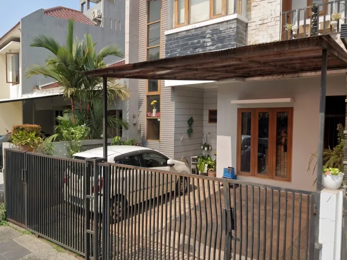 Two-story modern house with a metal gate, carport, and white car parked in the driveway behind a black fence.