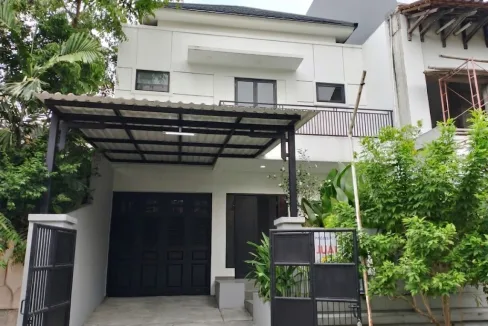 Modern Two story House with White Exterior Black Doors and a Metal Carport over a Driveway Surrounded by Greenery and a Black Gate  Rooma21com