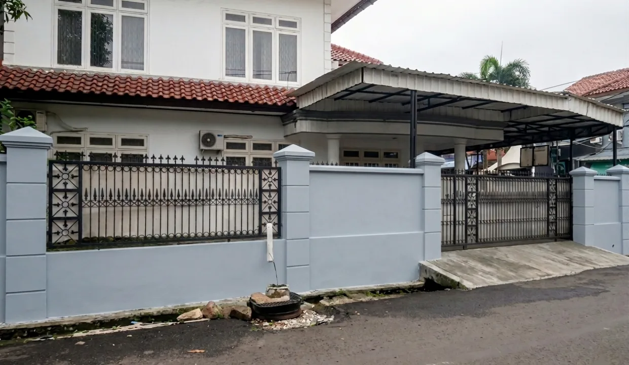 Facad Asli Rooma21.com Front View of a Two story House Behind a Pale Blue Boundary Wall and Decorative Black Wrought iron Fence with a Red Tile Roof and Carport Rooma21com