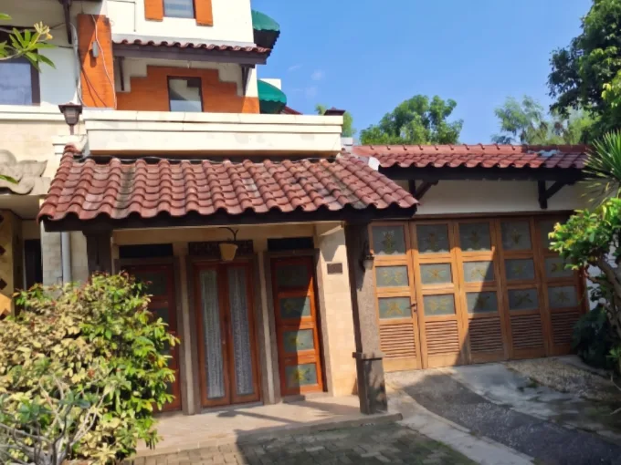Two story House with Red tiled Roof and Wooden Doors Set Along a Brick paved Driveway Under a Clear Blue Sky  Rooma21com